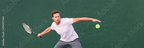 Tennis game man athlete hitting ball during match point on indoors tennis court at fitness health club. Panorama banner on green background.