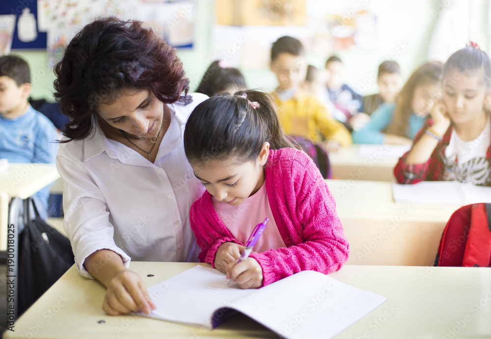 Teacher teaches to write to the girl student in the class Teacher teaches to write to the girl student in the class