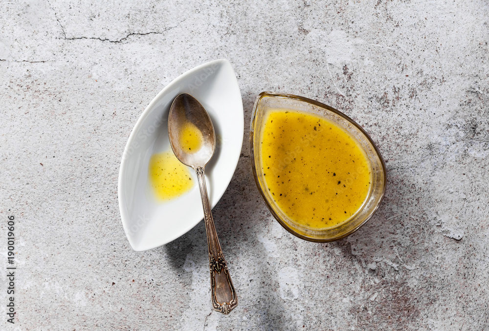 Ταπετσαρία dressing for salad from olive oil and lemon in a serving dish and a silver spoon