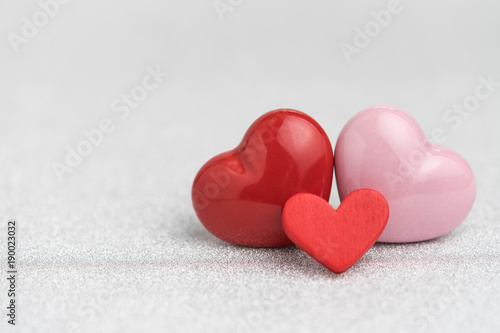 Valentines, wedding card or background with Red and pink heart shapes on glitter reflective particle white paper with copyspace