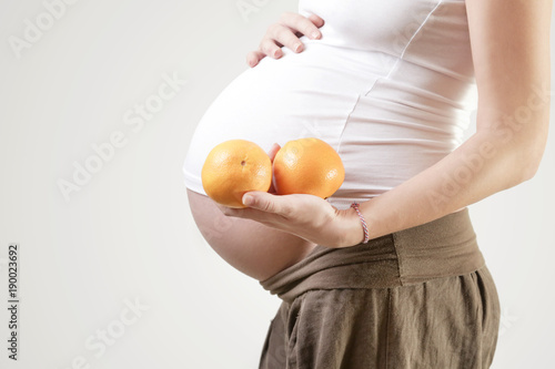 Pregnant woman holding oranges - studio shot