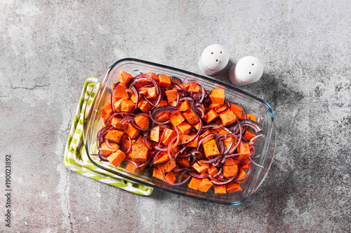 sweet potatoes in a baking sheet baked with onion, ready for serving on a stone table