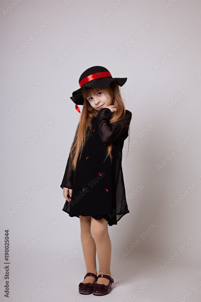 little girl smiling in a black dress and black hat with a red ribbon little girl smiling in a black dress and black hat with a red ribbon