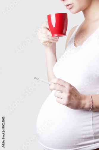 Pregnant woman drinking coffee and holding a cigarette
