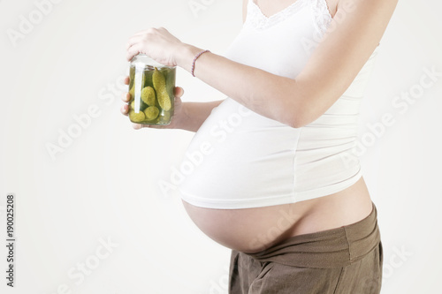 Pregnant woman holding jar of pickles - pregnancy food craving concept photo