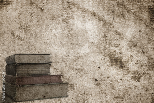 Background page design for a photo book, scrapbook or wallpaper in antique brown; abstract stone texture with image of stack of old tattered books photo