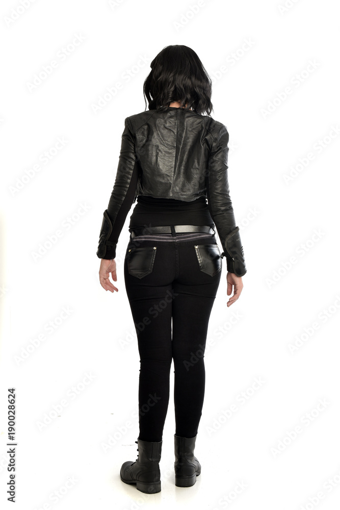 full length portrait of black haired girl wearing leather outfit. standing pose view from behind, on a white background full length portrait of black haired girl wearing leather outfit. standing pose view from behind, on a white background