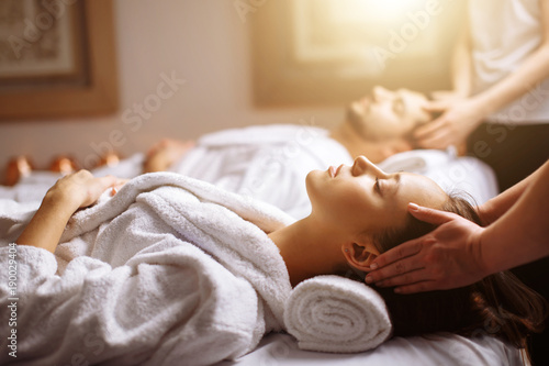 Young couple receiving head massage at beauty spa photo