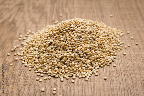 Golden Quinoa seed. Pile of grains on the wooden table. Selective focus.