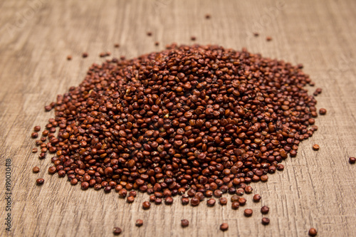 Red Quinoa seed. Pile of grains on the wooden table. Selective focus.