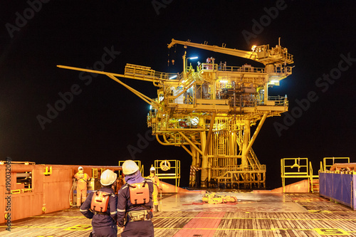 Two worker in offshore oil and gas operation discussion about platform before transfer to working on platform in night ship during stand in supply boat