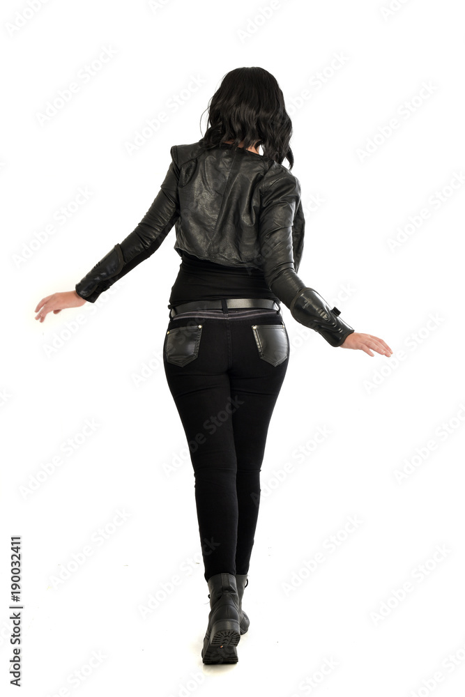 full length portrait of black haired girl wearing leather outfit. standing pose view from behind, on a white background full length portrait of black haired girl wearing leather outfit. standing pose view from behind, on a white background