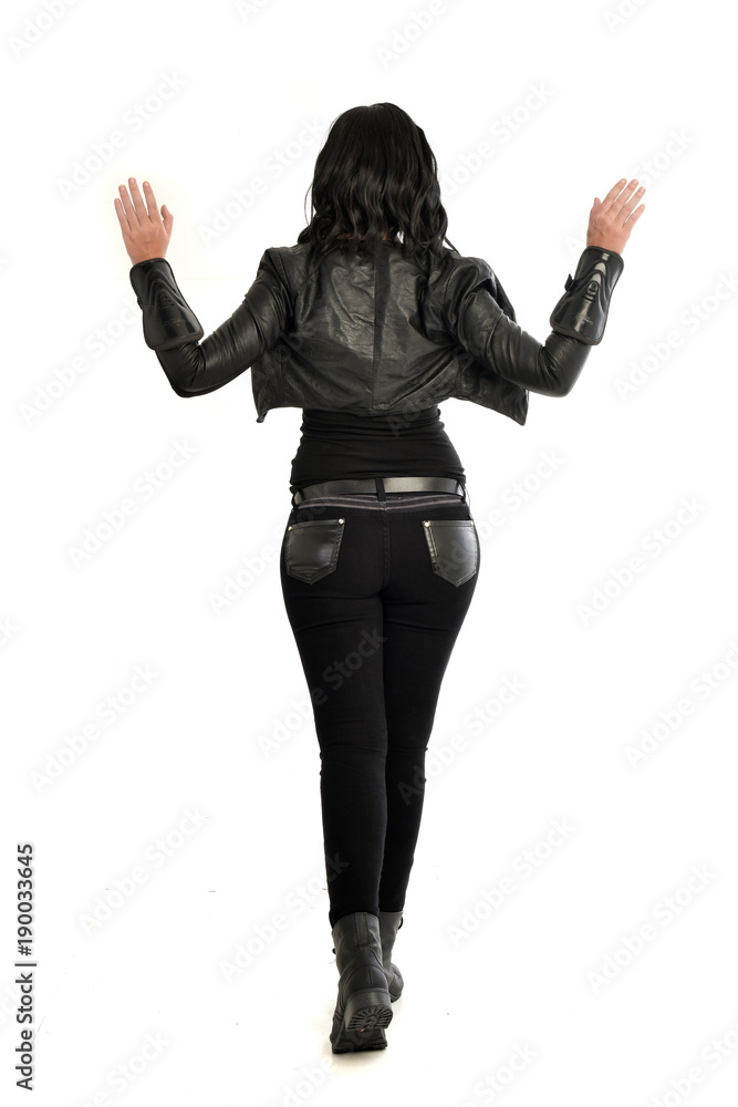 full length portrait of black haired girl wearing leather outfit. standing pose view from behind, on a white background full length portrait of black haired girl wearing leather outfit. standing pose view from behind, on a white background