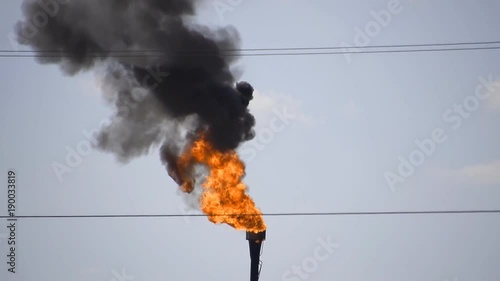 The smoking gas torch. Environmental pollution. System of a torch on an oil field. Burning through a torch head.