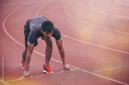 Man runner starting in the track. Fit male fitness runner jogging in stadium