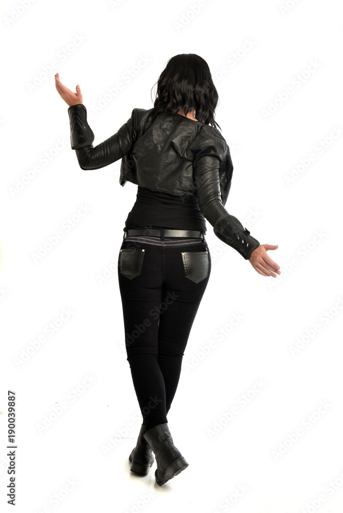 full length portrait of black haired girl wearing leather outfit. standing pose view from behind, on a white background full length portrait of black haired girl wearing leather outfit. standing pose view from behind, on a white background