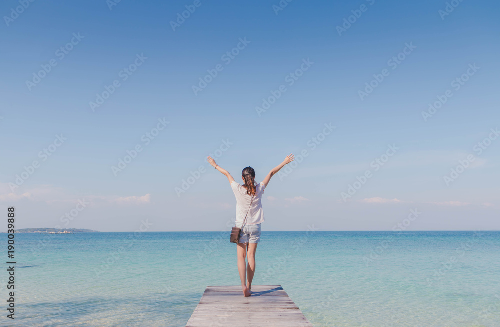 Traveler woman feeling happy on the bridge to the summer sea background.Concept of relax on vacation holidays. Traveler woman feeling happy on the bridge to the summer sea background.Concept of relax on vacation holidays.
