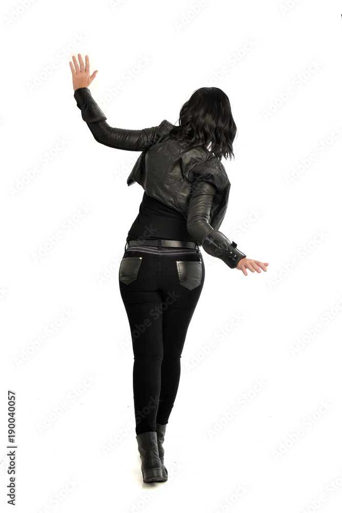 full length portrait of black haired girl wearing leather outfit. standing pose view from behind, on a white background full length portrait of black haired girl wearing leather outfit. standing pose view from behind, on a white background