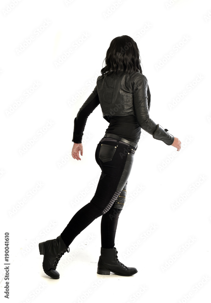 full length portrait of black haired girl wearing leather outfit. standing pose view from behind, on a white background full length portrait of black haired girl wearing leather outfit. standing pose view from behind, on a white background