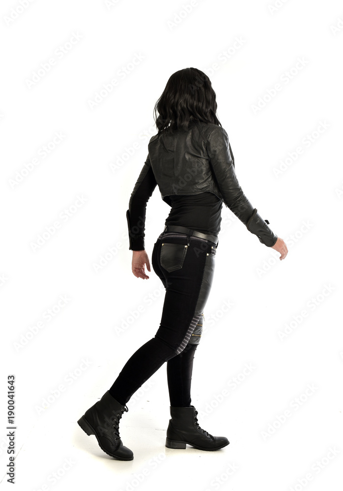 full length portrait of black haired girl wearing leather outfit. standing pose view from behind, on a white background full length portrait of black haired girl wearing leather outfit. standing pose view from behind, on a white background