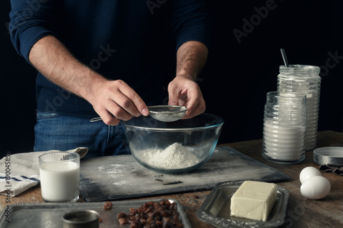 Male hands sifts flour for cooking dough Easter cross buns