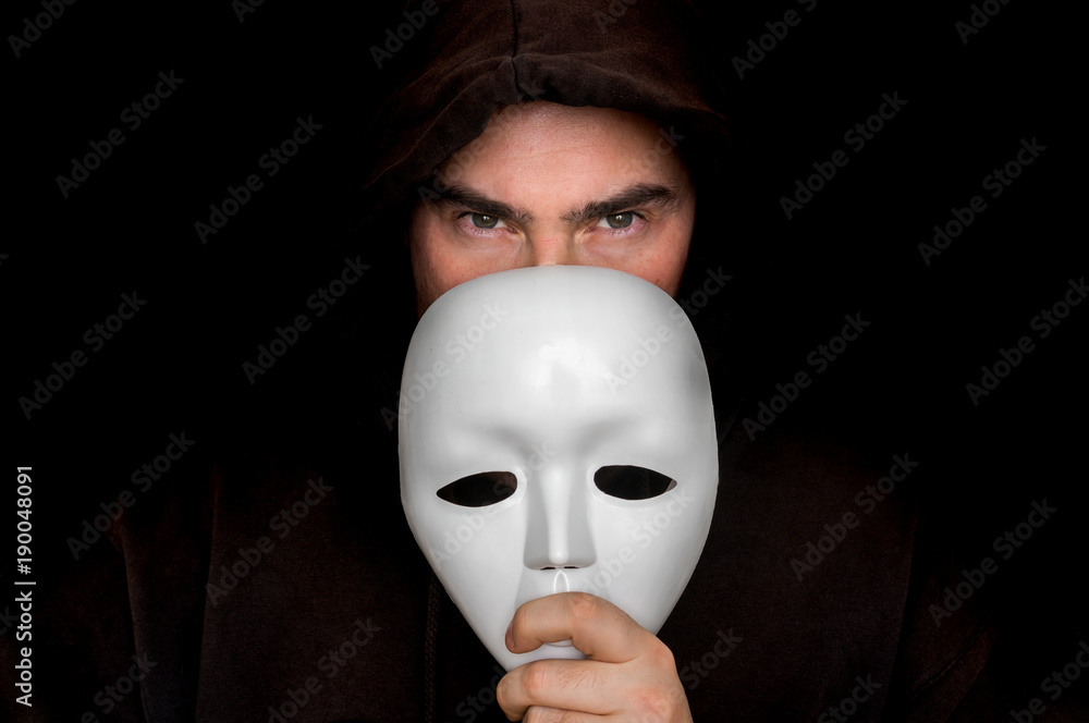 Mysterious man in black hiding his face behind white mask Stock Photo |  Adobe Stock