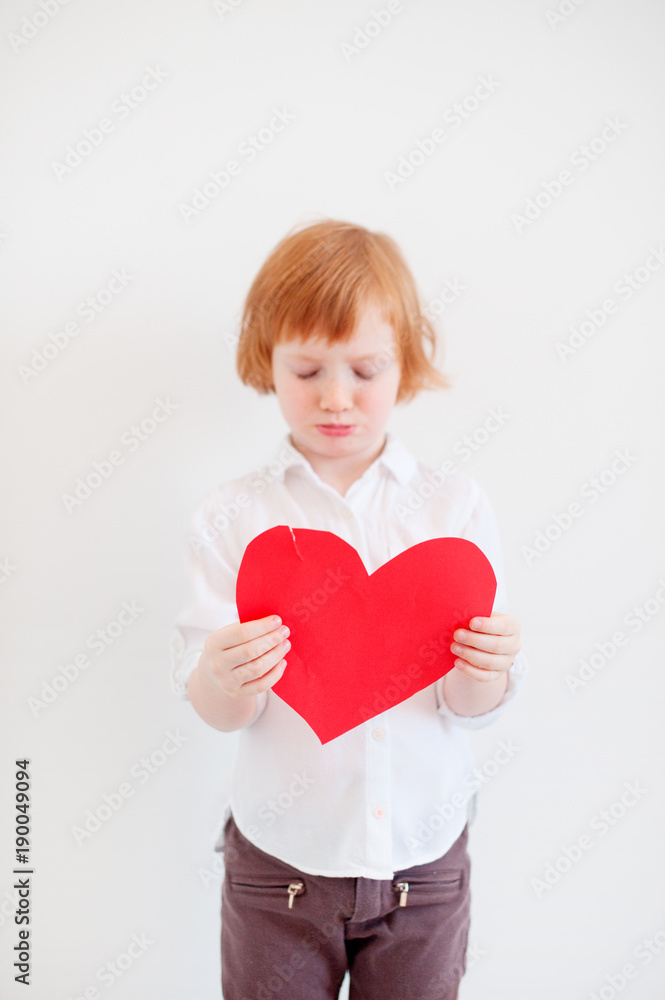 Red-haired girl holding a torn valentine in her hands Red-haired girl holding a torn valentine in her hands