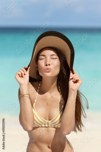 Cute beach woman blowing a kiss with sun hat