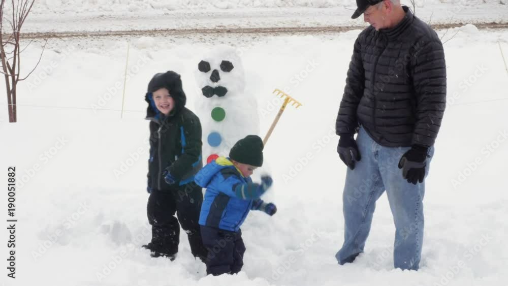 Grandpa makes a snowman with his grandchildren Grandpa makes a snowman with his grandchildren