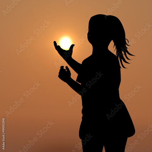Silhouette of girl holding the sun in her hands