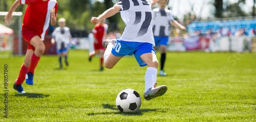 Soccer Football Kick. Young Player Kicking Soccer Ball. Footballers Running the Ball © matimix