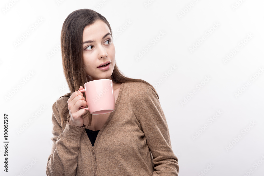 What is that. Charming young woman drinking coffee and looking to the side, reacting to some noises in the distance, seemingly slightly concerned What is that. Charming young woman drinking coffee and looking to the side, reacting to some noises in the distance, seemingly slightly concerned