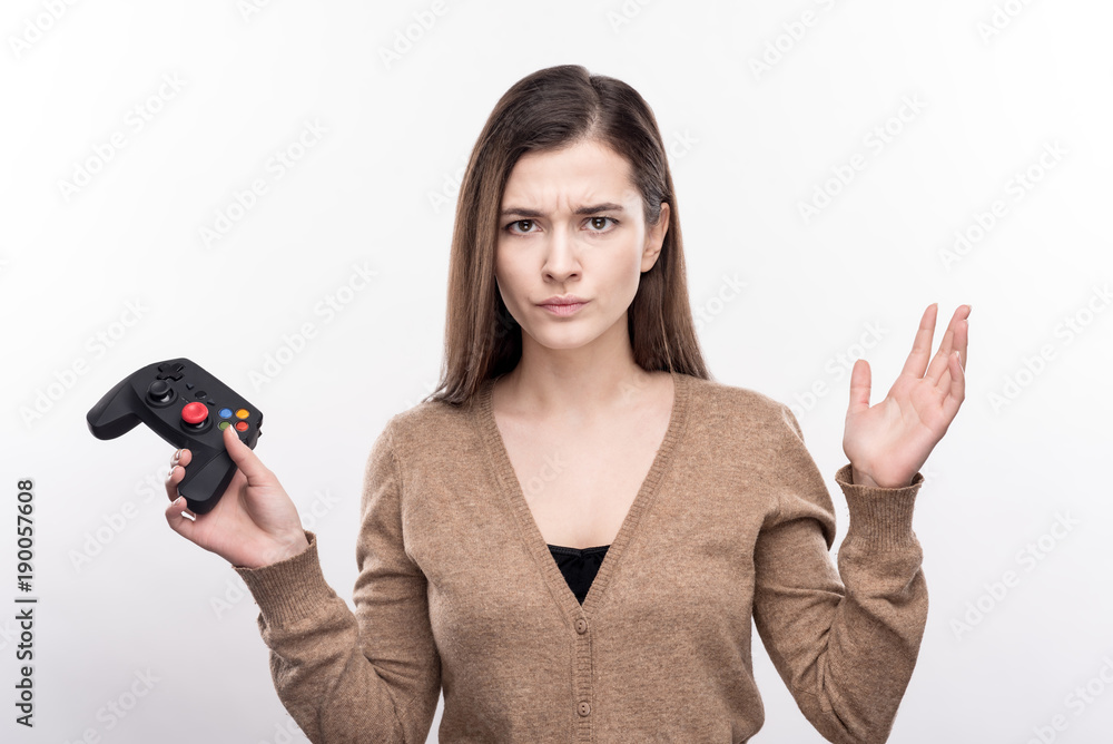Unfairly defeated. Pretty young woman looking angry, sulking about her loss in the video game while holding a game controller Unfairly defeated. Pretty young woman looking angry, sulking about her loss in the video game while holding a game controller
