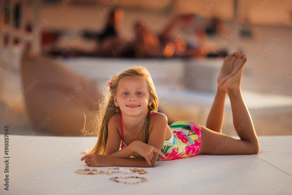 Naklejka premium Lovely girl with long hair lies on the beach against the sunset background