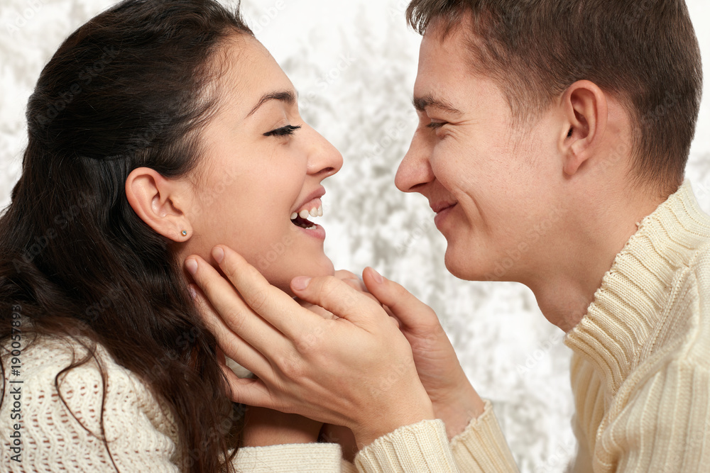 couple portrait near window with winter season, dressed in white, face closeup, love and holiday concept couple portrait near window with winter season, dressed in white, face closeup, love and holiday concept