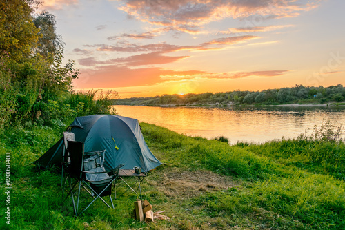 Camping by the river. Tents and camping equipment.