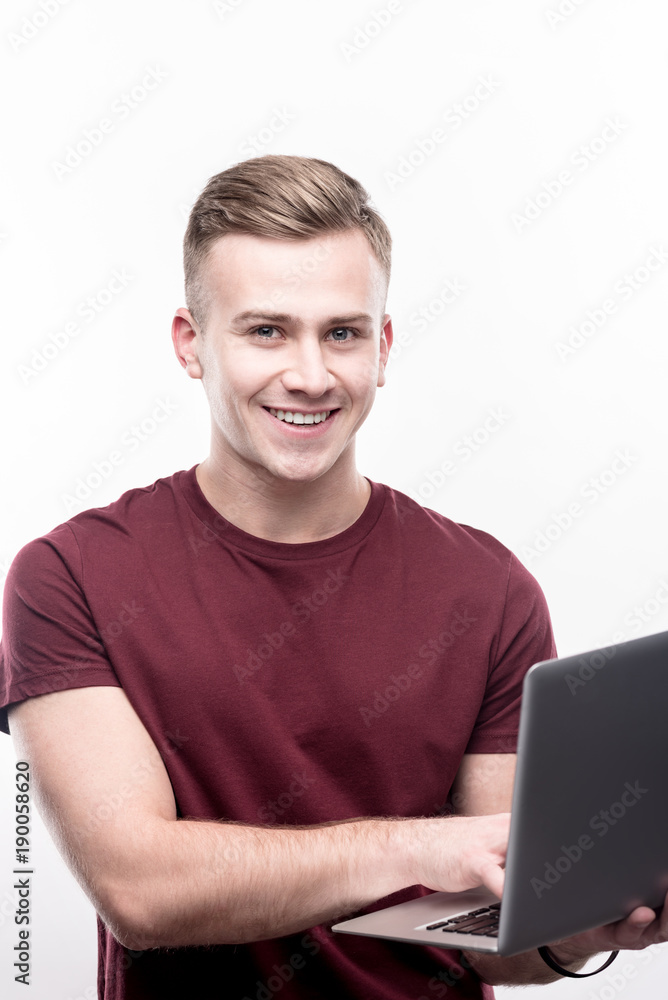 Best IT specialist. Handsome fair-haired young man in a burgundy t-shirt working on his IT project and posing for the camera while being isolated on a white background Best IT specialist. Handsome fair-haired young man in a burgundy t-shirt working on his IT project and posing for the camera while being isolated on a white background