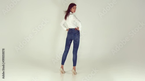 A young and happy girl in stylish jeans on a white background