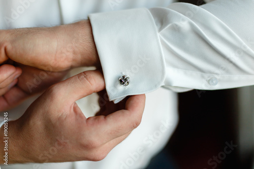 Foto A man wears buttons of cufflinks on the sleeves of the white shirt