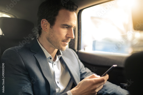 Man texting on his smart phone while traveling by car