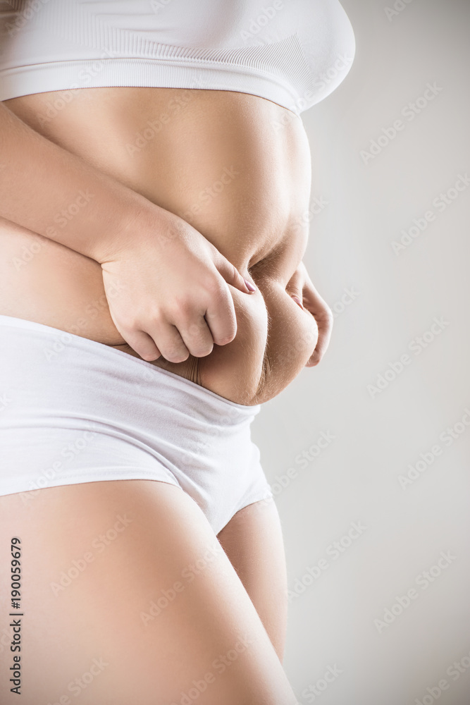 Woman in white underwear holds belly fat. Stock Photo