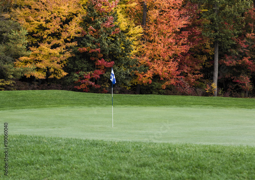 Golf course putting green with autumn foliage. photo