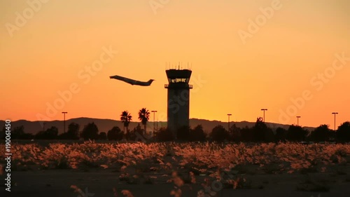 Plane takes off at sunset by air traffic tower at Hollywood Burbank Airport