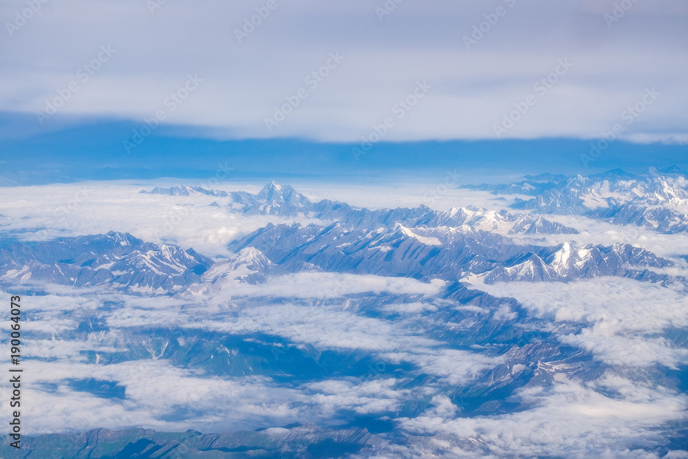 View from airplane window above the clouds with blue sky and cloudscape in sunlight morining. white wispy cirrus and cirrostratus clouds