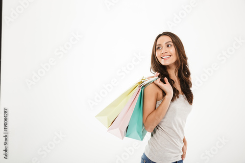 Horizontal picture of trendy woman posing on camera with shopping packs in hand, isolated over white wall copy space
