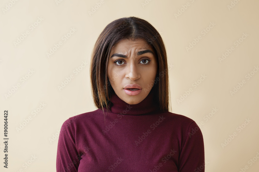 What do you mean. Portrait of confused young Afro American female feeling puzzled and indignant, raising one eyebrow and keeping mouth opened, expressing confusion, misunderstanding or dissatisfaction What do you mean. Portrait of confused young Afro American female feeling puzzled and indignant, raising one eyebrow and keeping mouth opened, expressing confusion, misunderstanding or dissatisfaction