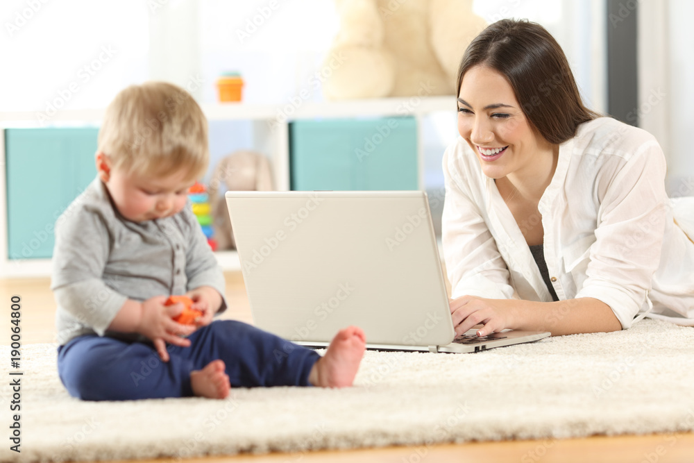Mother working with a laptop and baby playing Mother working with a laptop and baby playing