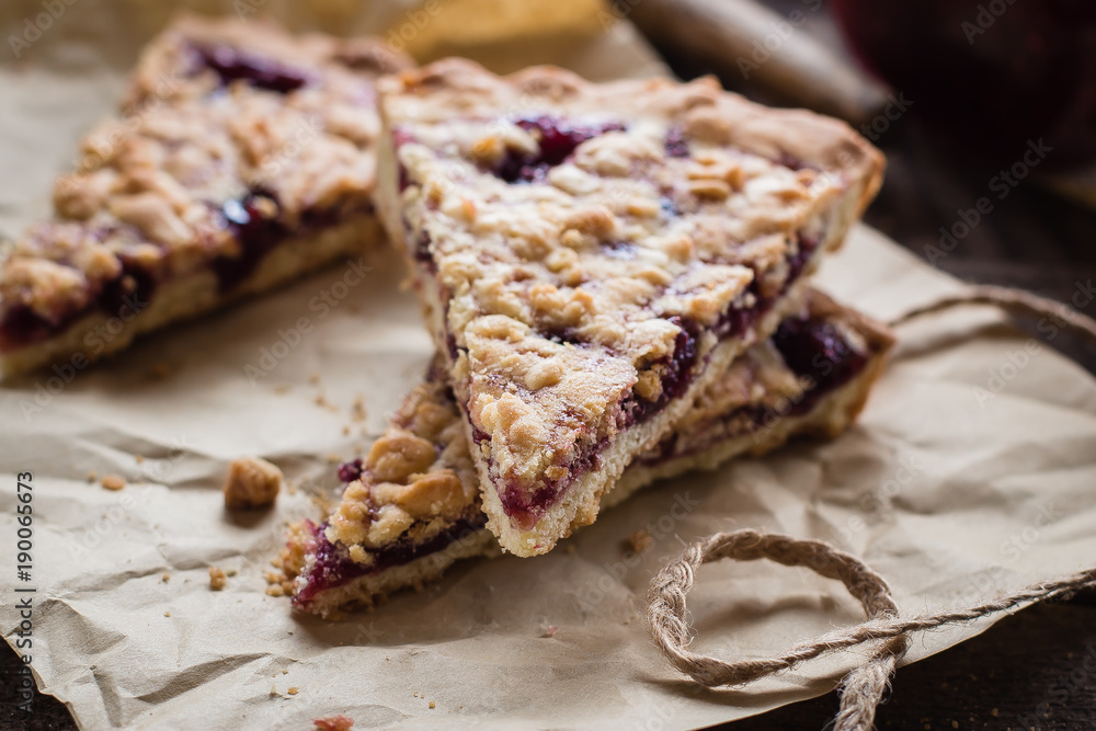 Homemade tasty shortcrust raspberry pie with crumble on old wooden table background. Jam Tart Pieces Snack Food. Closeup