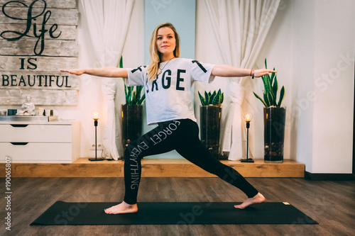 VILNIUS, LITHUANIA - NOVEMBER 2017 - One calm woman (20-30 years old) the yoga coach sits in a pose on the rug in a cozy studio.