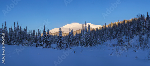 Winter wildlife mountain landscape with the top mountains lit by sunlight. Panoramic photo. © Rustic